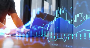 Ofis masasındaki dizüstü bilgisayarda iki kez finansal diyagrama maruz kalan tanınmamış iş adamı elleri. Yatırım ve borsa kavramı