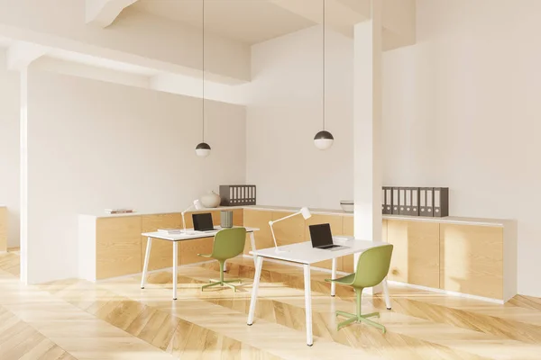 Corner of modern open space office with white walls, wooden floor, white computer tables with green chairs and laptops and wooden cabinets. 3d rendering