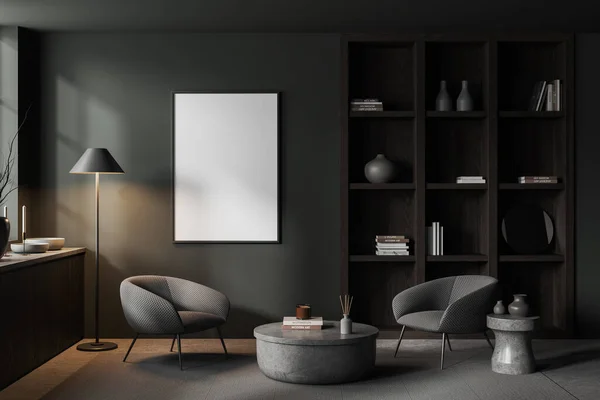 Interior of stylish home library with gray walls, concrete floor, two gray armchairs standing near round coffee table, bookcase and mock up poster. 3d rendering