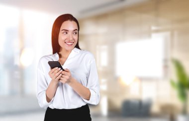 Telefonla çalışan mutlu bir iş kadını bulanık ofis fotokopi arkaplanından mutlu bir şekilde bakıyor. Çevrimiçi ağ kavramı ve başlat