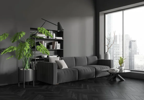 Dark living room interior with sofa and coffee table, side view, shelf with books and big plant. Panoramic window on Singapore skyscrapers. Mockup copy space wall. 3D rendering