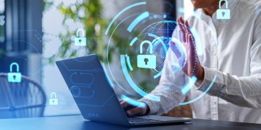 Bulanık ofiste dizüstü bilgisayar kullanan tanınmayan bir iş adamı. Çift taraflı siber güvenlik arayüzü ve plante hologram kullanıyor. Veri koruması kavramı