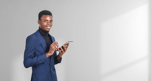African businessman standing with tablet, successful portrait with gadget on copy space empty white background. Concept of digital connection, internet and social media
