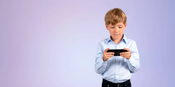 一个穿着正装 拿着智能手机 站在紫色背景上看屏幕的严肃小男孩的画像 电子学习和社交媒体的概念 游戏和技术 复制空间 — 图库照片