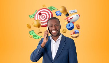 Elinde akıllı telefonuyla gülümseyen siyah iş adamı, turuncu arka planda renkli başlangıç simgeleri. Dartboard, ampul ve roket havalandı. İş fikri ve başarı kavramı