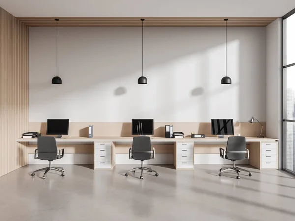 Minimalist coworking interior with armchairs and pc computer on work desk in row, concrete floor. Business office room with panoramic window on skyscrapers. 3D rendering
