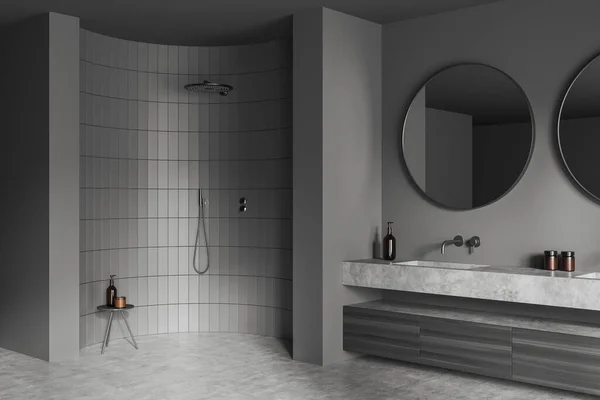 2つの大きなラウンドミラー シャワー シンク グレーの壁 液体石鹸 コンクリート床とスツールと暗いバスルームのインテリアのコーナービュー 水処理の概念 3Dレンダリング — ストック写真