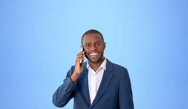 Akıllı telefondan konuşan mutlu iş adamı, fotokopi masmavi arka planda gülümseyen portre. Başarı kavramı, iyi haber, kariyer ve gelişme