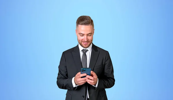 入力してオンラインでテキストメッセージを使用して幸せなビジネスマン 黒の正式なスーツで笑顔の肖像画 コピースペース空の青の背景 ソーシャルメディアとビジネスネットワークの概念 — ストック写真