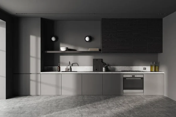 Interior of stylish kitchen with gray walls, concrete floor, comfortable gray cabinets with built in cooker, oven and sink and dark wooden cupboards. 3d rendering