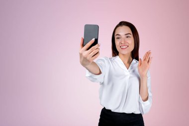 Akıllı telefonlu bir iş kadını, video görüşmesinde gülümsüyor ve konuşuyor, eflatun kopya alanı arka planı. Çevrimiçi iletişim ve ağ kavramı