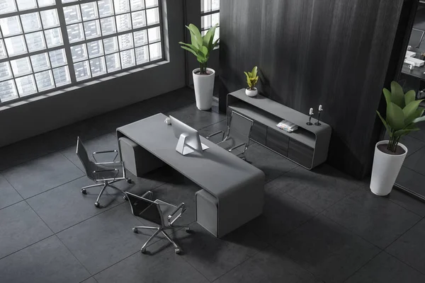 Top view of dark business room interior with desk and armchairs on grey tile floor. Pc computer and sideboard with decoration. Panoramic window on skyscrapers. 3D rendering
