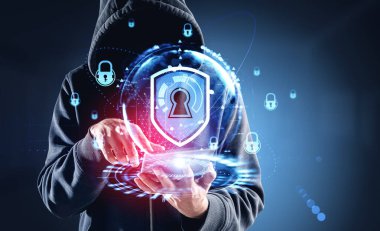 Günlük kıyafet giyen hackerın elinde dijital arayüzlü tablet var. Hologram asma kilit ve anahtar deliği var. Karanlık arka plan. Veri ve bilgi koruması, mahremiyet ve güvenlik kavramı