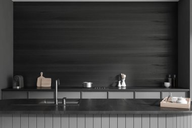 Bar adası, lavabo ve sobası olan karanlık bir mutfak. Kaşık ve yağ şişeli mutfak gereçleri, kuvars güvertesinde tepsi. Modern minimalist yemek pişirme alanı. Kara tahta boş duvar. 3B görüntüleme