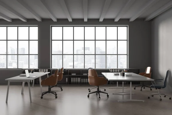 グレーの壁 コンクリートの床 茶色とグレーの椅子と大小のコンピュータテーブルと現代のコワーキングオフィスのインテリア フォルダとの本棚や街並みと大きな窓 3Dレンダリング — ストック写真