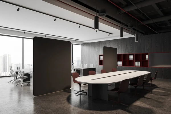 Interior of modern office meeting room with white walls, concrete floor, long conference table with red chairs and open space area separated by two gray partition panels. 3d rendering