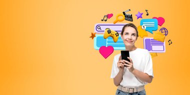 Telefonla genç kadın portresi hayal etmek, fotokopi uzayının turuncu arka planındaki çeşitli dijital dünya simgelerine bakmak. Sosyal medya, iletişim ve uygulamalar kavramı