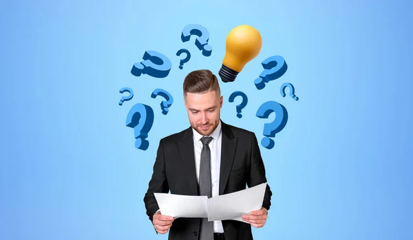 Concentrated businessman with documents in hands, floating question marks icons with light bulb on blue background. Concept of business start up, idea and plan