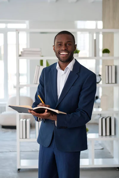 Leende Afroamerikansk Affärsman Formell Kostym Står Och Antecknar Anteckningsboken Tittar — Stockfoto