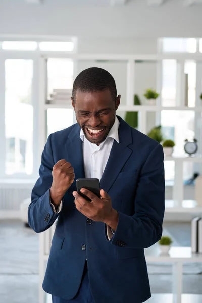 正式なスーツを着ている素晴らしいアフリカ系アメリカ人のビジネスマンは オフィスの職場でスマートフォンを保持しています モデル ビジネスマン 時間管理 衝撃を受けた 驚いた男の概念 — ストック写真