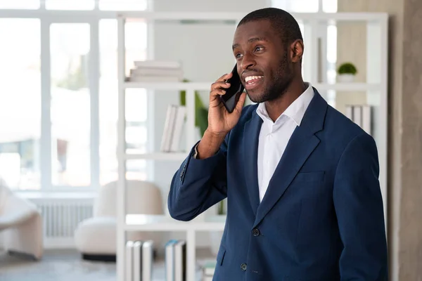 フォーマルスーツを着たアフリカ系アメリカ人のビジネスマンは オフィスの職場でスマートフォンで話しています モデル ビジネスパーソン タイム管理 デバイス ガジェットのコンセプト — ストック写真