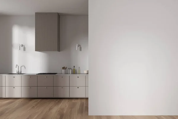 Interior of modern minimalistic kitchen with white walls, wooden floor, beige cabinets with built in cooker and sink and copy space wall on the right. 3d rendering
