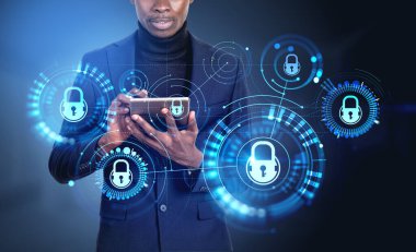 Afrikalı işadamı tabletle çalışıyor, sanal ekranda kilit gövde hologramı, parlayan daireler ve bağlantı hatlarıyla çalışıyor. Veri koruma ve güvenlik kavramı
