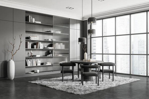 Dark living room interior with dining table and chairs, side view shelf with decoration. Eating corner and carpet on grey concrete floor. Panoramic window on skyscrapers. 3D rendering