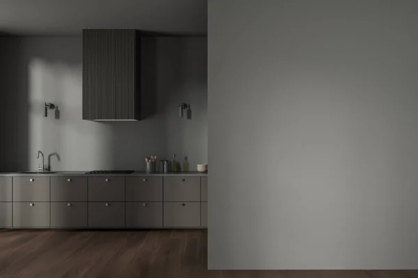 Interior of stylish minimalistic kitchen with gray walls, dark wooden floor, gray cabinets with built in cooker and sink and copy space wall on the right. 3d rendering