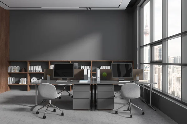 グレーで暗い木製の壁 コンクリートの床 椅子が付いている大きいコンピュータ テーブルおよびそれらの上のコピー スペースの壁が付いている本棚が付いているスタイリッシュなオープンスペース オフィスの内部 3Dレンダリング — ストック写真