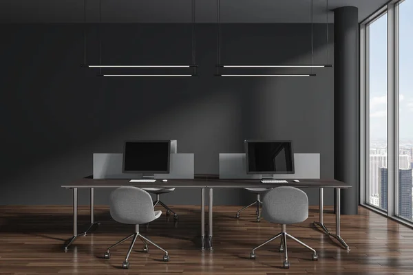 Stock image Dark coworking interior with armchairs and pc monitors on desk with partition, hardwood floor. Corporate office workspace and panoramic window on New York skyscrapers. 3D rendering