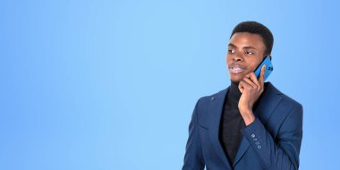 Takım elbiseli ve balıkçı yaka kazaklı ciddi bir Afro-Amerikan iş adamının portresi mavi fotokopi alanının arkasında duruyor. İletişim kavramı