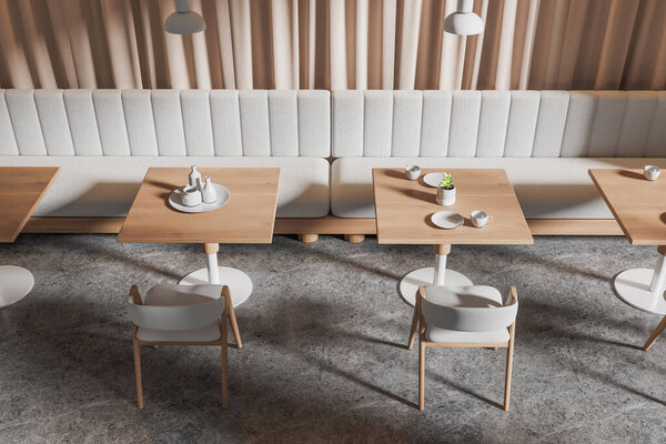 Вид сверху современного кафе с бежевыми шторами, каменным полом, удобными белыми софами, стоящими возле квадратных столов с белыми стульями. 3d-рендеринг
