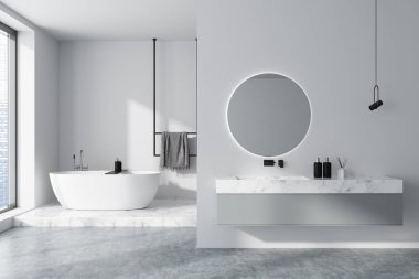 Beyaz banyo içi lavabo ve güverte aksesuarlarla dolu, köşesinde mermer kürsüde banyo ve raylarda havlu. Gökdelenlerde panoramik pencere, gri beton zemin. 3B görüntüleme