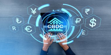 İnsan eliyle dizüstü bilgisayarda yazma görüntüsü, CBDC hud hologramı ve farklı parlayan ülkelerin para birimi simgeleriyle sanal ekran. Dijital varlık ve kripto bankacılık kavramı