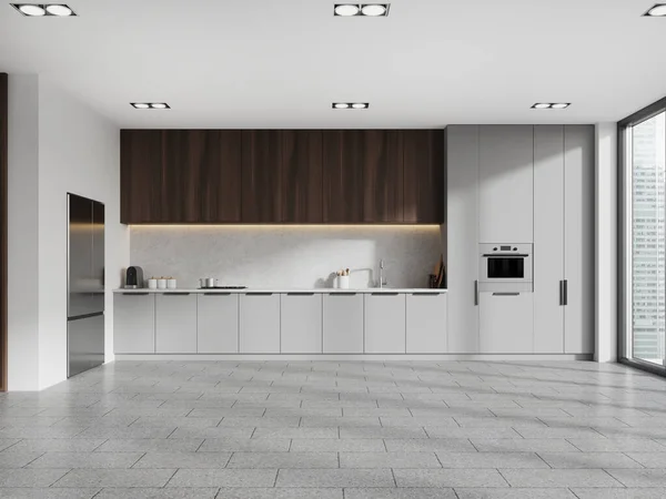Interior of modern kitchen with white walls, tiled floor, gray cabinets with built in sink and cooker, dark wooden cupboards, big fridge and window. 3d rendering
