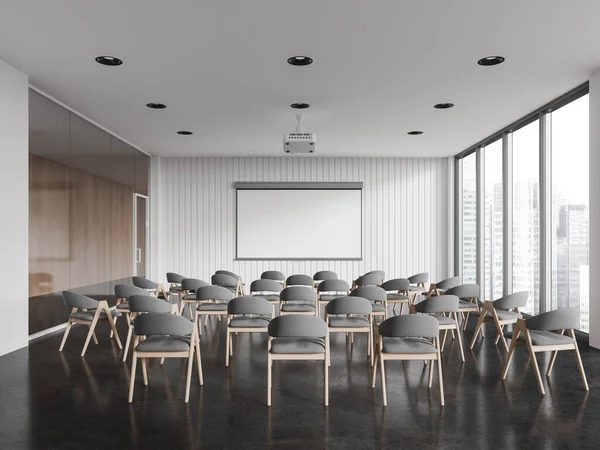 Interior of modern conference hall with white and glass walls, concrete floor, rows of gray chairs and mock up projection screen. Business training and conference concept. 3d rendering