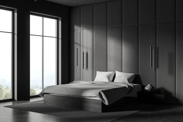 Grey hotel bedroom interior with bed and nightstand with books and decoration, side view carpet on grey concrete floor. Relax corner with panoramic window on countryside. 3D rendering