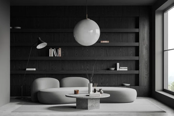 グレーウォール コンクリートフロアのスタイリッシュなリビングルームのインテリア ラウンドコーヒーテーブルとダークウッドの本棚の近くに立っている快適なグレーのソファー 3Dレンダリング — ストック写真