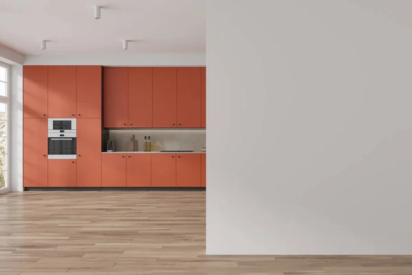 Interior of modern kitchen with white walls, wooden floor, comfortable orange cupboards and cabinets with built in sink and oven and copy space wall on the right. 3d rendering