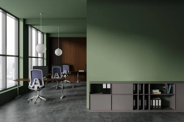 Interior of stylish open space office with green and wooden walls, concrete floor, row of computer desks with blue chairs and copy space wall above gray cabinet with folders. 3d rendering
