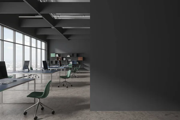 Interior of stylish open space office with gray walls, concrete floor, massive computer desks with green chairs and colorful bookshelves. Copy space wall on the right. 3d rendering