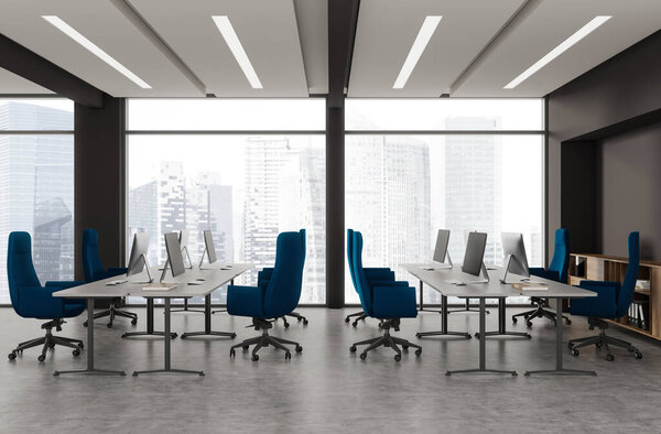 Интерьер стильного открытого пространства офиса с серыми стенами, бетонный пол, ряд черных компьютерных столов с синими стульями и панорамное окно с городским пейзажем. 3d-рендеринг