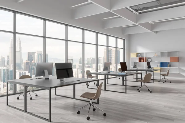 Corner of modern open space office with white walls, wooden floor, massive computer desks with beige chairs and colorful bookshelves. Panoramic window with cityscape. 3d rendering