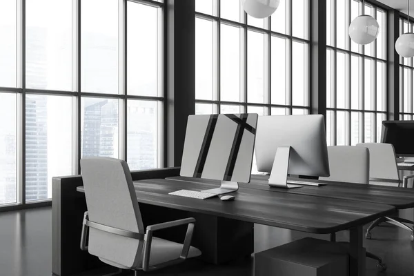 Interior of stylish open space office with gray walls, concrete floor, computer monitor with black screen standing on dark wooden table with gray chair and panoramic window. 3d rendering