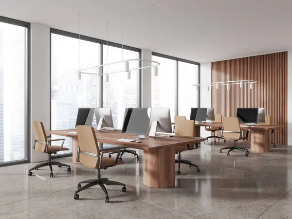 Corner of modern open space office with white and wooden walls, beige tiled floor, rows of massive wooden computer tables with brown chairs standing near panoramic windows. 3d rendering
