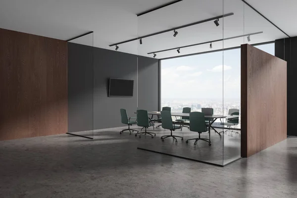 Corner of stylish meeting room with wooden and gray walls, concrete floor, long conference table with green chairs and big TV set on the wall. 3d rendering