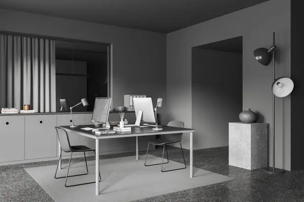 Dark office interior with pc computers on a shared table, side view sideboard with folders and decoration. Cozy workspace with carpet on grey granite floor. 3D rendering