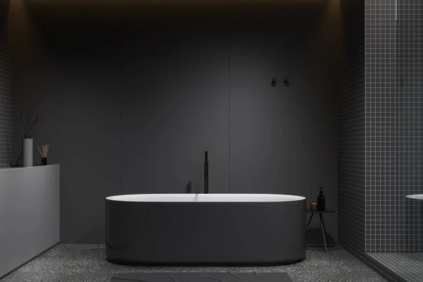Dark home bathroom interior with bathtub on grey granite floor. Bathing space with tub and side table, accessories and minimalist decoration. 3D rendering