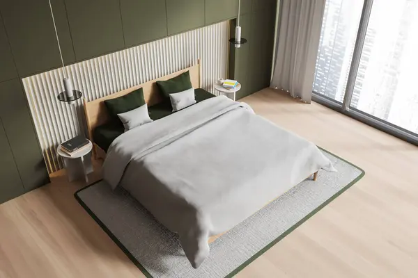 Top view of green home bedroom interior with bed and nightstand, carpet on hardwood floor. Sleeping corner in minimalist studio apartment with panoramic window on skyscrapers. 3D rendering
